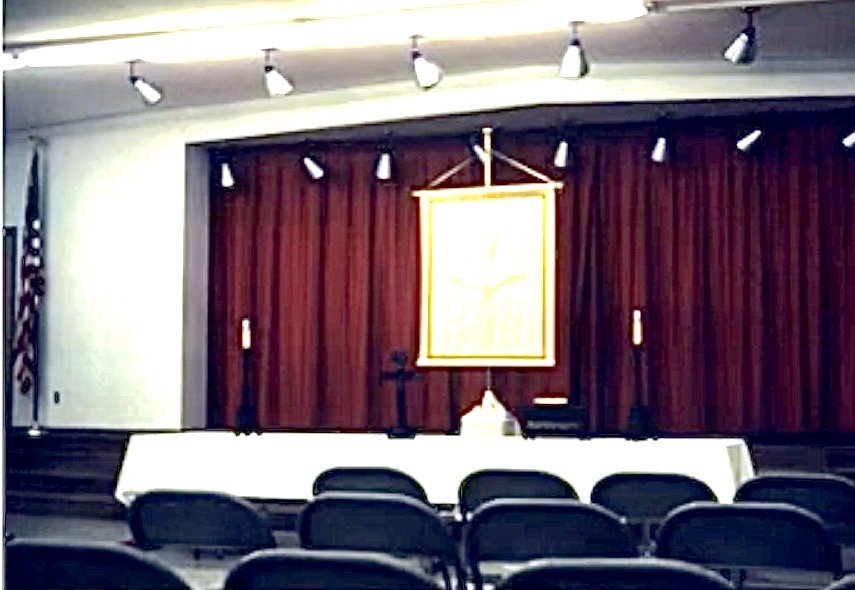 Rows of folding chairs facing the temporary altar in the school cafeteria.