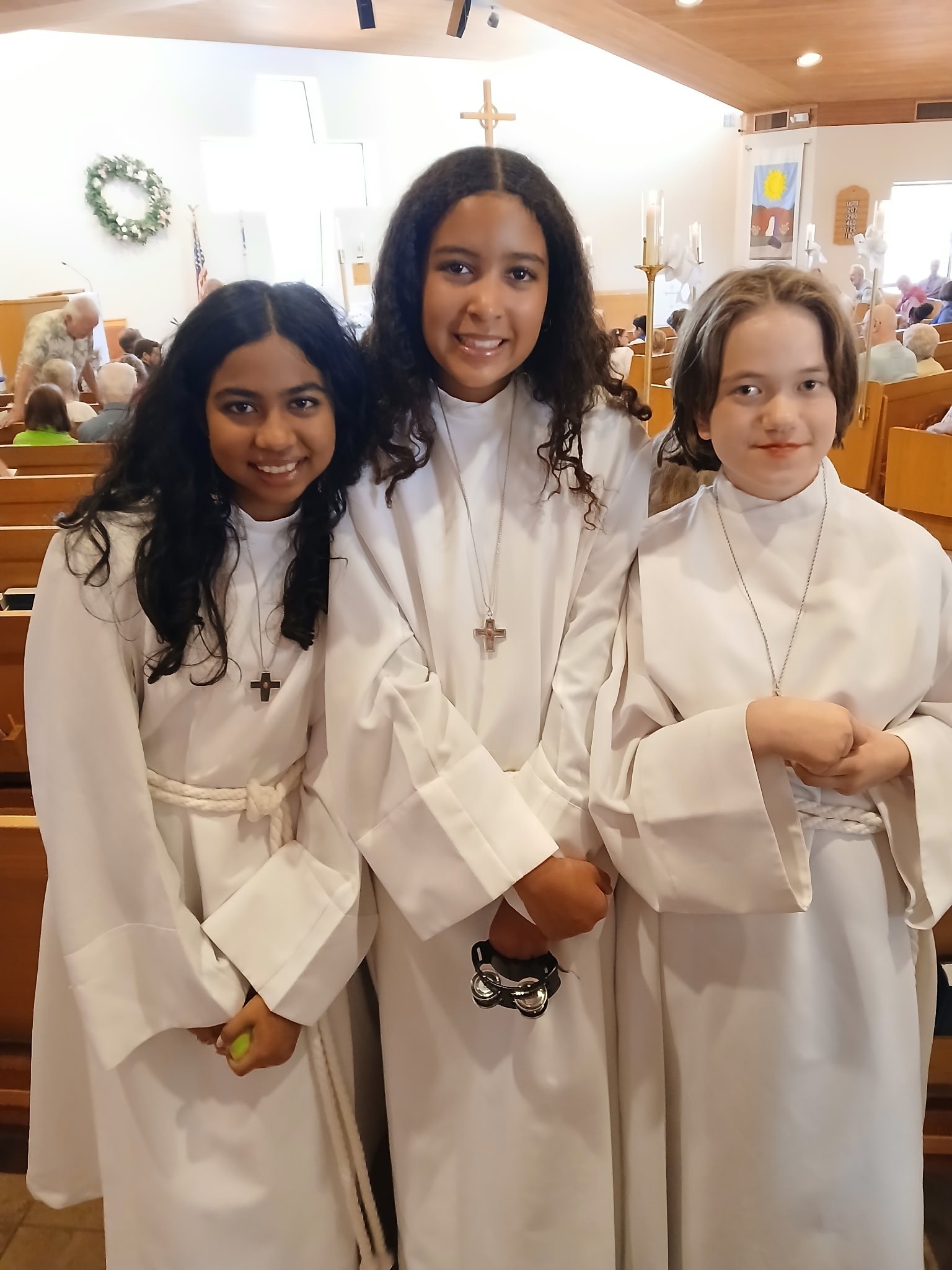 Three young people in white robes at St. Alban’s.
