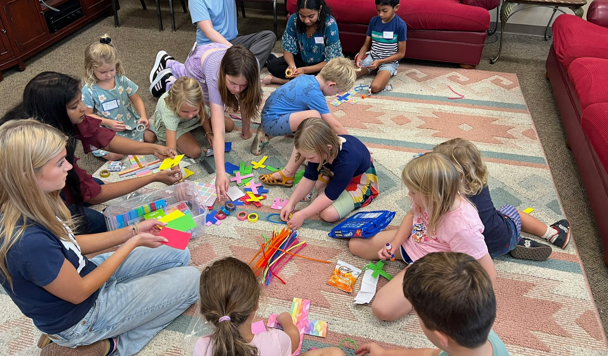 Children making colorful crafts together on the floor.