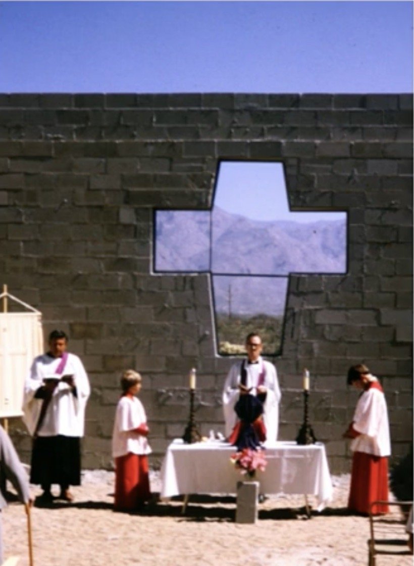 Clergy at an outdoor altar beneath the chapel’s cross-shaped window.